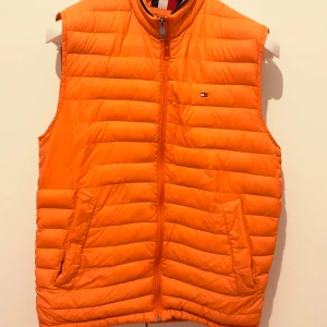 Orange dunväst från Tommy Hilfiger - Tommy Hilfiger väst – ÄKTA Västen är klassisk design. Bra passform och kvalité. Sparsamt använd. Pris: 299kr