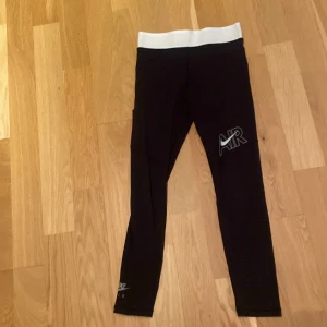 Svarta Nike AIR leggings med vit midja - Säljer ett par svarta leggings från Nike med bred vit resår i midjan där det står 'AIR'. Byxorna har även en stor AIR-logga med swoosh på benet. Perfekta för dig som gillar sportig stil. Är ca 160 och de är litte för korta 