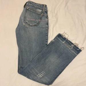 Blå jeans med slitningar  - Säljer ett par low waist blå jeans med slit . Jeansen har fina detaljer  med broderad text på bakfickan. Jeansen är köpa i en butik i barcelona.Kontakta för ytligare info och bilder. Priset går även att diskutera jag sänker ofta priiset