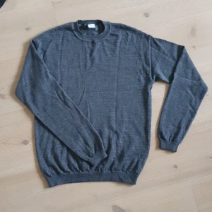 Mörkgrå stickad tröja av merinoull - Mysig mörkgrå stickad tröja från Lindex  med rund halsringning och långa ärmar. Gjord av merinoull så perfekt för kyligare dagar och enkel att matcha med olika outfits. Öppen för prisförslag!