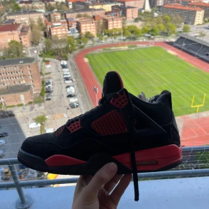 Nike Air Jordan 4 Retro Black/Red - Säljer ett par Nike Air Jordan 4 Retro i svart och rött. Skorna har klassisk mesh och skinn, med snörning och den ikoniska Jumpman-loggan på hälen. Perfekta sneakers för dig som gillar streetwear och vill sticka ut med en fet färgkombo.