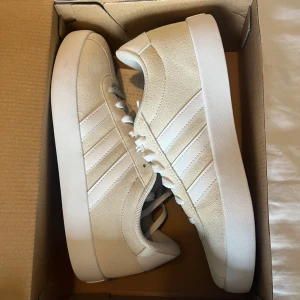 Beige Adidas sneakers med vita detaljer - Säljer ett par lätta fina ljus beiga adidas skor. Ej använda 