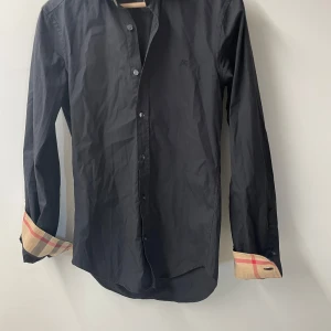 Burberry skjorta  - Tja, säljer denna Burberry skjorta för endast 499kr. Det har lossnat en del av en knapp som syns på sista bilden. Pridet är absolut förhandlingsbart🙌