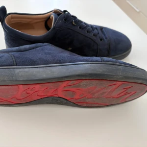 Mörkblå loubs sneakers i mocka - Säljer ett par mörkblà loubs utan spikar.Storlek 40 men passar 41. Knappen är lite av vid snörena. De är i bra skick. Dock har jag inte boxen