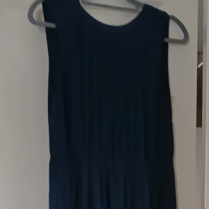 Mörkblå ärmlös klänning - Säljer en elegant mörkblå klänning med ärmlös design och rund halsringning. Klänningen har ett mjukt, lätt veckat tyg som ger en fin siluett. Perfekt för dig som vill ha en stilren look..Om det behövs kan jag skicka bättre bilder på klänningen vid intresse 