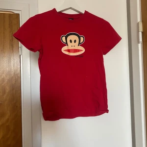 Röd baby-tee med apa från Paul Frank - Röd babytee från Paul Frank med klassiskt apa-tryck framtill och färgglad logga på ryggen. Rund halsringning och korta ärmar. Perfekt för dig som gillar färg och lekfull stil. Köpt här på Plick❤️