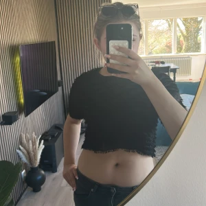 Svart croppad t-shirt - Säljer en svart croppad t-shirt med korta ärmar. Enkel och stilren modell som passar perfekt till jeans eller kjol. T-shirten har en rak passform och är tillverkad i ett mjukt material.