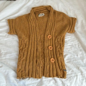 stickad kofta  - Säljer en kortärmad, stickad kofta i brun gul färg från Nümph som inte går att hitta på affär längre! Snygga stickade detaljer och mönster längs hela plagget. Storlek xs, passar bra på mig som bär xs/s. Orginalpris: 1000 kr