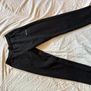 Svarta mjukisbyxor från Champion - Svarta mjukisbyxor från Champion med liten vit logga på vänster höft. Byxorna har resår i midjan och är tillverkade i mjukt bomullsmaterial. Skriv för funderingar 