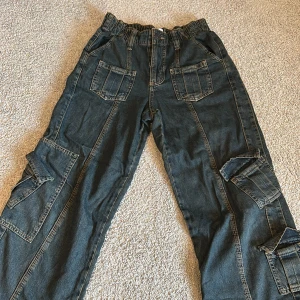 Blå cargopants  - Säljer ett par blå cargopants med flera fickor på benen och framtill. Byxorna har resår i midjan och raka ben. Använda bara några få gånger 