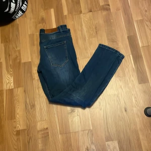 Blå jeans från Denim DAY - Säljer ett par klassiska blå jeans från Denim AY i storlek W31. Jeansen har fem fickor, normal passform och snygga slitningar framtill för en trendig look. Perfekta till vardags och lätta att matcha med olika outfits.