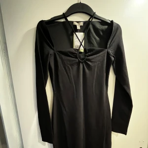 Svart långklänning  - Säljer en svart långklänning med lång ärm. Klänningen har en smickrande passform och en enkel, stilren design. Perfekt för dig som gillar minimalistisk stil och vill ha något klassiskt i garderoben.