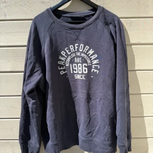 Mörkblå sweatshirt från Peak Performance - Säljer en mörkblå sweatshirt från Peak Performance med tryck framtill: 'Peak Performance 1986'. Tröjan har rund halsringning och långa ärmar. Perfekt för en avslappnad stil. Sitter som XL!