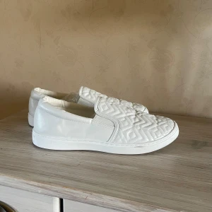 Vita slip-on sneakers - Säljer ett par vita slip-on sneakers. Passar bra till student klänning. Använda en gång. 