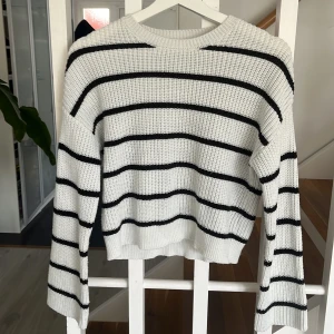 Vit stickad tröja med svarta ränder från Kappahl - Vit stickad tröja från Kappahl med svarta horisontella ränder. Tröjan har rund halsringning och långa ärmar. Perfekt för en avslappnad och stilren look.