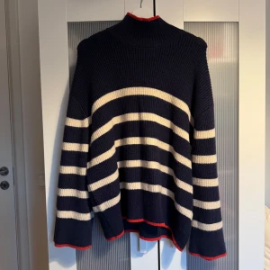 Randig stickad tröja med polokrage - Mysig stickad tröja med breda marinblå och vita ränder samt röda detaljer vid krage, ärmslut och nederkant. Tröjan har polokrage och en oversized passform, perfekt för kyliga dagar. Skriv privat för fler bilder 🩷