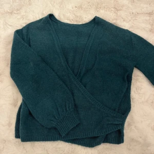 Blå omlottkofta från Linn Ahlborg x NA-KD - Mysig blå stickad omlottkofta från Linn Ahlborg x NA-KD. Koftan har långa ärmar, ribbade muddar och omlottdesign som ger en avslappnad och trendig look. Perfekt att slänga på sig över ett linne eller t-shirt.