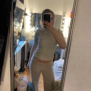 Beige ribbad topp från Lindex - Säljer en beige ribbad topp från Lindex i storlek S. Toppen har korta ärmar och ett unikt, strukturerat mönster som ger en cool look. Perfekt att styla med både jeans och kjol. Superbekväm och stretchig!