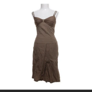 Brun klänning med smala axelband - Säljer en brun klänning med smala dubbla axelband och markerad byst. Klänningen har en lätt utsvängd kjol och ärmlös design. Perfekt för varma dagar och enkel att styla med accessoarer.
