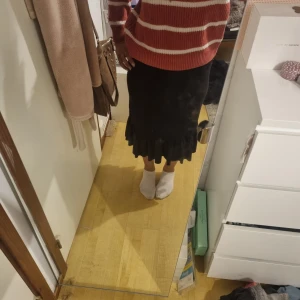 Svart långkjol med volangkant - Säljer en svart långkjol med volangdetalj längst ner. Kjolen har en rak passform och är enkel att matcha med olika toppar. Perfekt för dig som gillar stilrena plagg med en liten twist.