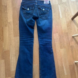 True Religion bootcut jeans med slitningar - Mörkblå lågmidjade bootcut jeans från Truereligion. Byxorna har slitningar framtill. De är omsydda till bootcut av en skräddare. Skriv för fler bilder eller mått!💘💘