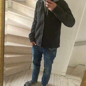 Mörkgrå overshirt från Bläck - Säljer en mörkgrå overshirt från Bläck med knäppning framtill och två bröstfickor. Perfekt för lager på lager. Säljer pga att den inte passar. Köpte i small men den var för lång🥲 Den är 65 cm lång och 45 cm bred. Köpt på MQ för 1000.