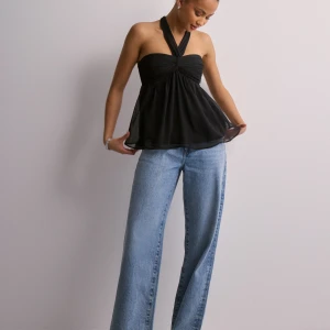 Svart halterneck topp - Säljer en svart halterneck topp med omlottkänsla och lätt utsvängd passform. Toppen är axelbandslös och har en snygg twistad detalj framtill. Perfekt för att skapa en trendig och stilren look.