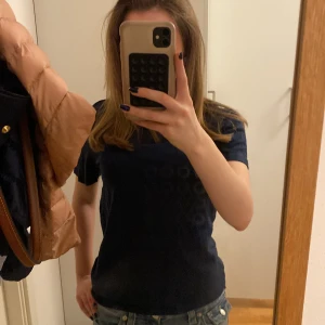 Mörkblå croppad t-shirt från Kappahl - Säljer en enkel och stilren mörkblå croppad t-shirt från Kappahl. T-shirten har korta ärmar och rund halsringning. Perfekt basplagg att matcha med jeans eller kjol.