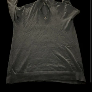 Ljusblå stickad polotröja - Säljer en ljusblå stickad polotröja med lång ärm och ribbade muddar. Tröjan har en klassisk polokrage med liten öppning framtill. Perfekt för kyligare dagar och enkel att matcha med olika outfits.