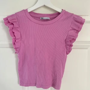 Rosa topp med volangärmar från Zara - Supersöt rosa ribbad topp från Zara med volangdetaljer på axlarna❤️Den är tyvärr inte min stil längre så därför säljer jag den men absolut inget fel på den. 