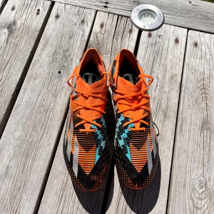 Adidas orange fotbollsskor. X speedportal messi.1 firm - Säljer ett par snygga fotbollsskor från Adidas i orange med svarta, vita och turkosa detaljer. Skorna har snörning och mönstrad ovansida för bättre bollkontroll. Perfekta för dig som vill sticka ut på planen! Köpta för 1 år sen å har använt dom ungefär 10 gånger. Säljer för de e för små för mig. Pris kan variera.