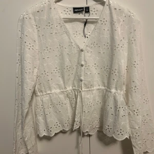 Vit härlig top - En härlig vit somrig top, perfect nu till sommaren. Toppen har knappar och ett band vid fronten.