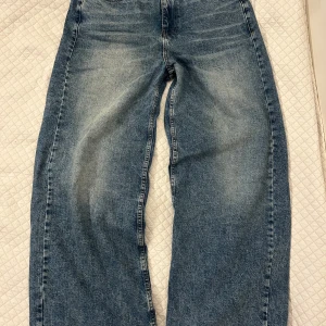 Blå wide leg jeans från Collusion - Säljer ett par blå jeans från Collusion med breda ben och klassisk femficksdesign. Jeansen har en avslappnad passform och är tillverkade i denim med ljusa slitningar framtill. Perfekta för en trendig och bekväm stil.