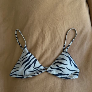 Zebramönstrad bikiniöverdel - Säljer en trendig bikiniöverdel med zebramönster i svart och vitt. Modellen har trekantskupor och smala axelband som går att justera. Perfekt för sommaren och strandhäng!