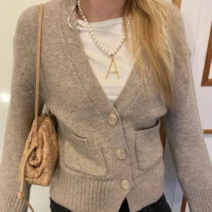 Kofta från Gina tricot  - Mysig beige stickad kofta med stora knappar framtill och två fickor. Koftan har lång ärm och ribbade muddar vid ärmslut och nederkant. Perfekt att slänga på sig över en t-shirt för en avslappnad look.