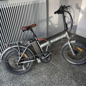 RAWBIKE elcykel - Säljer en RAWBIKE elcykel i grått med breda däck, brunt sadel och pakethållare bak. Cykeln har hopfällbar ram, digital display på styret och robusta skärmar. Perfekt för stadskörning och pendling.