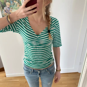 Grön- och vitrandig topp från Lindex - Säljer en grön- och vitrandig topp från Lindex med v-ringning och korta ärmar. Tröjan är omsydd från L till S. Jätte söt tröja till sommaren💗