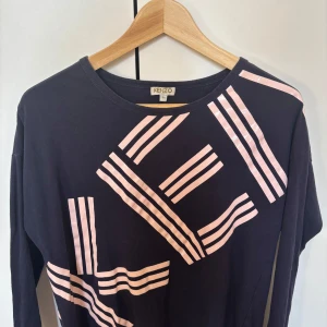 Mörkblå långärmad tröja från Kenzo - Säljer en mörkblå långärmad tröja från Kenzo med rosa grafiskt mönster 💙Tröjan har en rund halsringning och är perfekt för en stilren look. Passar bra till både jeans och kjol. Perfekt för dig som gillar att sticka ut med stil!🌟