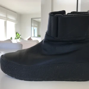 Svarta boots Vagabond Stl 38 - Svarta varmfodrade boots från Vagabond. Stl 38. Äkta skinn. Skorna har en stilren design med dragkedja på sidan för enkel på- och avtagning. Använda ett fåtal gånger, är i mkt bra skick, inga defekter. Nypris 1600kr