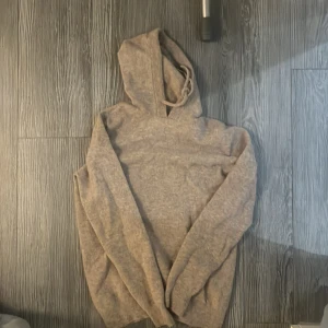 Beige cashmere hoodie - Säljer en mysig beige hoodie med långa ärmar. Perfekt för kyliga dagar och avslappnade stunder. Huvan ger extra värme och stil. Passar bra till jeans.