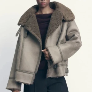 Brun/Grå jacka med teddyfoder - Säljer en snygg beige jacka med mjukt teddyfoder. Jackan har bältesdetaljer vid midjan. Perfekt för kyliga dagar! Använd fåtal gånger och kommer i mycket bra skick! 