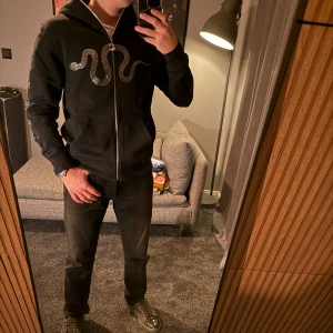Svart rhinestone full zip hoodie - Säljer en svart full zip rhinestone hoodie från cldst. Nästan alla stenar sitter kvar och tröjan har riktigt bra kvalité. Perfekt för en stilren och avslappnad look. Väldigt unik då den har full zip up, dvs dragkedja ända upp på luvan. Kommer ej ihåg nypris, har för mig att det var runt 700kr, jag säljer för endast 300kr. Bara att höra av sig vid minsta lilla fundering, pris går att diskutera svid snabb och smidig affär. 