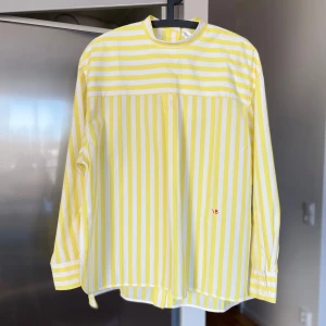 Victoria Beckham - Gul och vit randig skjorta från Victoria Beckham. Stl 40. Knäppning i rygg. Slitsar i sidan. Oversize stl. Ny aldrig använd. 