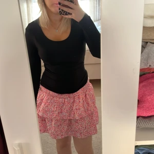 Rosa blommig volangkjol - Söt rosa kortkjol med blommigt mönster och volangdetaljer. Använt en gång. 