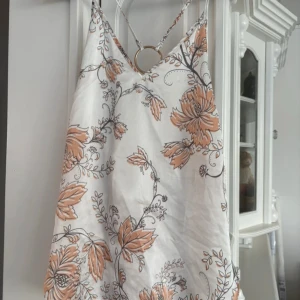 Blommig linnetopp från Bik Bok - Säljer en snygg blommig linnetopp från Bik Bok i storlek L. Toppen har ett vackert mönster med stora blommor i orange och svart på en vit bakgrund. Den har smala axelband och en avslappnad passform, perfekt för sommardagar.