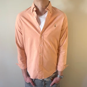 Persikofärgad Ralph Lauren skjorta - Nu säljer vi ännu en fet polo skjorta som passar till alla tillställningar! Du ska kunna uttrycka stil utan att det kostar för mycket!🕺🍾💼🤩  Storlek👔: M Nypris💰:  ca 1499 kr