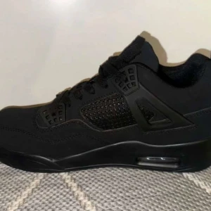 Jordan 4 black cats - Säljer ett par svarta Nike Air Jordans med klassisk design och snörning. Skorna har en stilren look med synlig luftdämpning i sulan för extra komfort. Perfekta för dig som vill ha en ikonisk sneaker i garderoben. Passar storlek 42,43,44