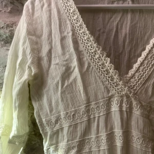 Vit klänning med spetsdetaljer - Säljer en vacker vit klänning med spetsdetaljer och v-ringning. Klänningen har trekvartsärmar och fina broderade mönster. Perfekt för sommartillfällen💕 har även en vit klänning under(kan skicka bild på den om det behövs) 💕