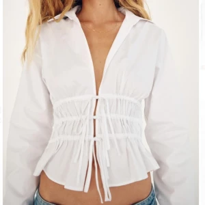 Vit blus med snörning från Zara - Säljer en stilren vit blus från Zara med snörning i midjan som ger en snygg passform. Blusen har långa ärmar och en klassisk krage. Perfekt för att ge en extra touch till din outfit.✨✨