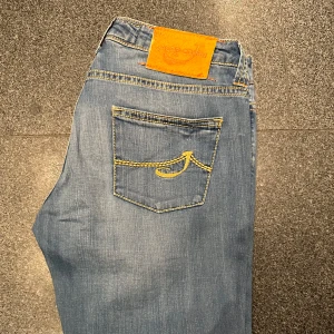 Blå Jacob Cohën jeans  - As feta Jacob Cohën jeans i ljusblå/grå färg. Det är en gammlare mer eftertraktad modell med Jacob Cohën loggan på bakfickan. Jeansen passar någon som är max 165 cm lång och 28W i midja. Inga defekter. 